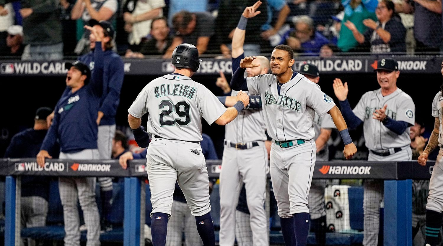 Cal Raleigh and Julio Rodríguez celebrate after Raleigh scores the Mariners’ go-ahead run in the ninth inning vs. the Blue Jays.